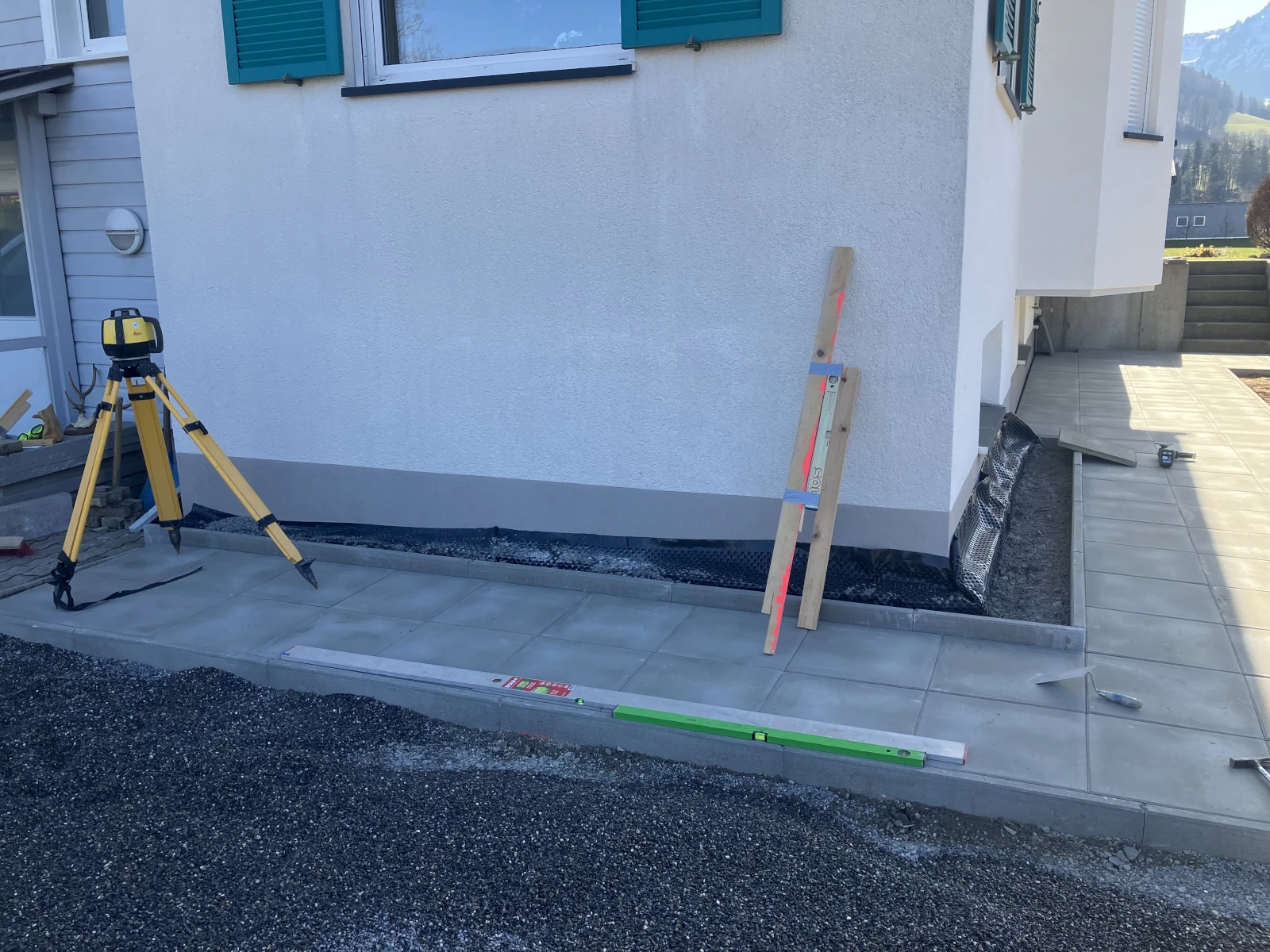 Pflasterarbeiten am Haus. Werkzeuge sind sichtbar.