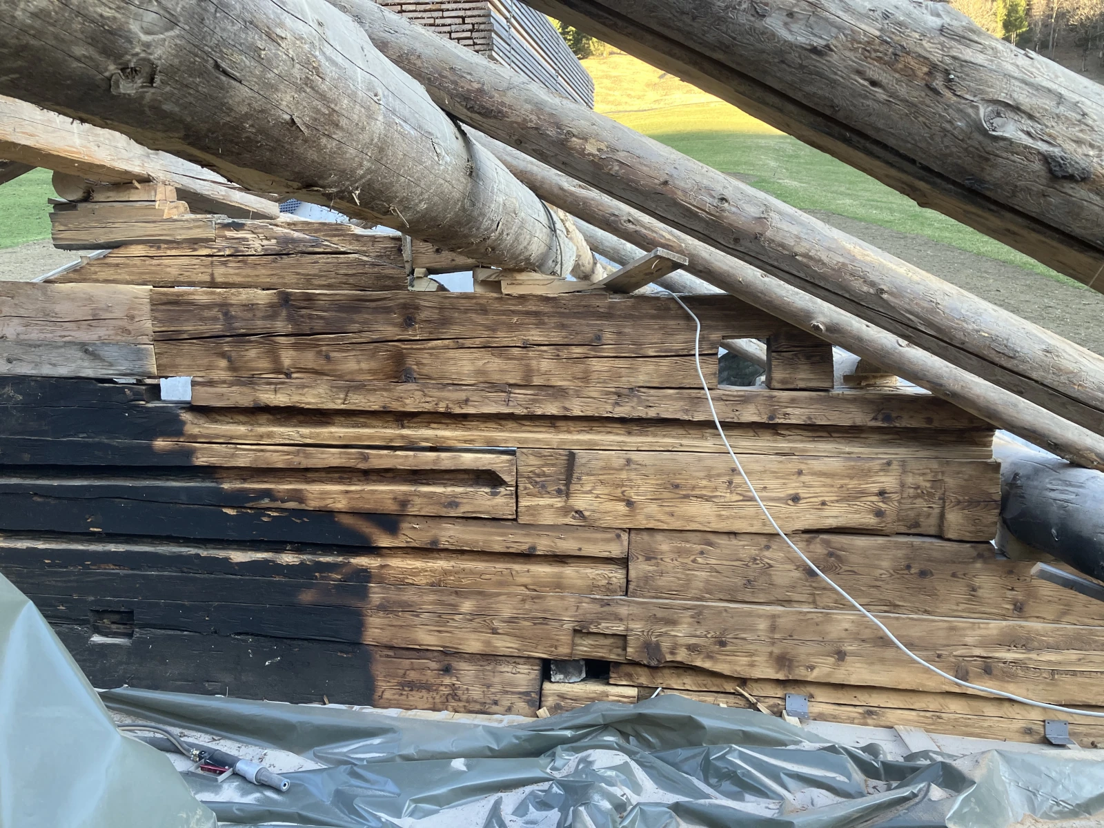 Ein rußgeschwärzter Dachstuhl der zur Hälfte mit dem Sandstrahler gereinigt wurde.