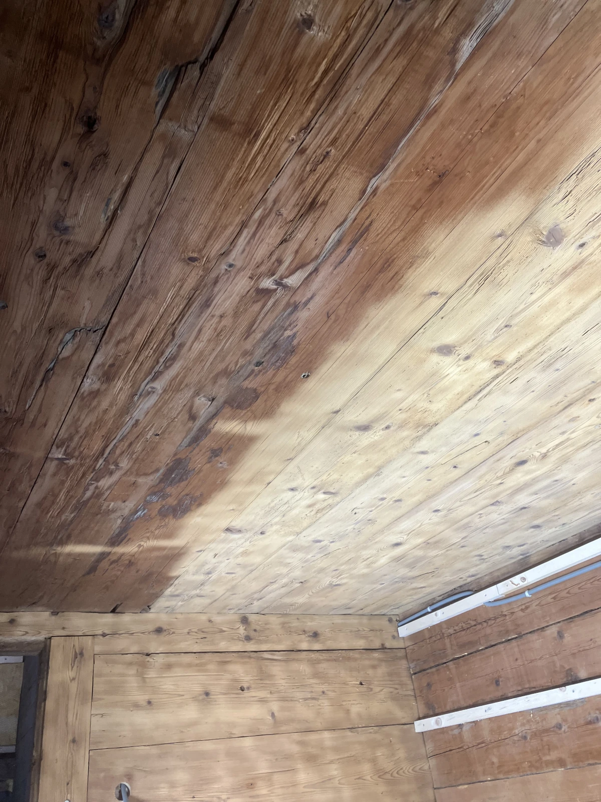 Eine Holzdecke die mit dem Sandstrahler zur Hälfte gereinigt wurde.