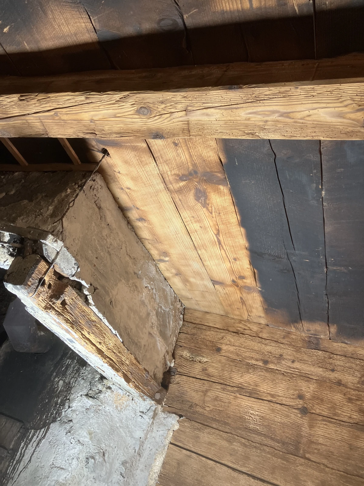 Eine rußgeschwärzte Holzdecke über einem Kamin die mit dem Sandstrahler zur Hälfte gereinigt wurde.