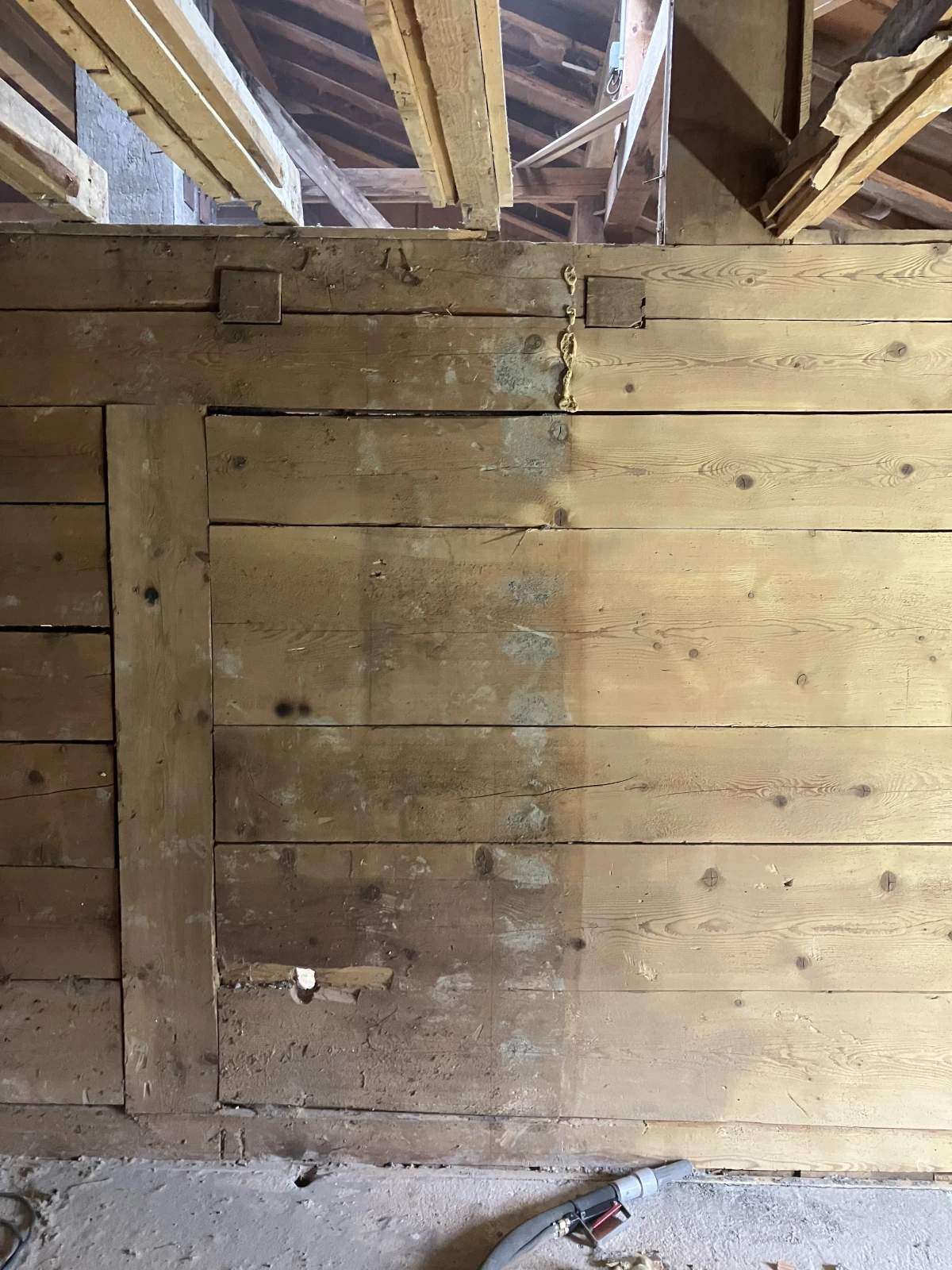 Eine Holzwand die mit dem Sandstrahler zur Hälfte gereinigt wurde.