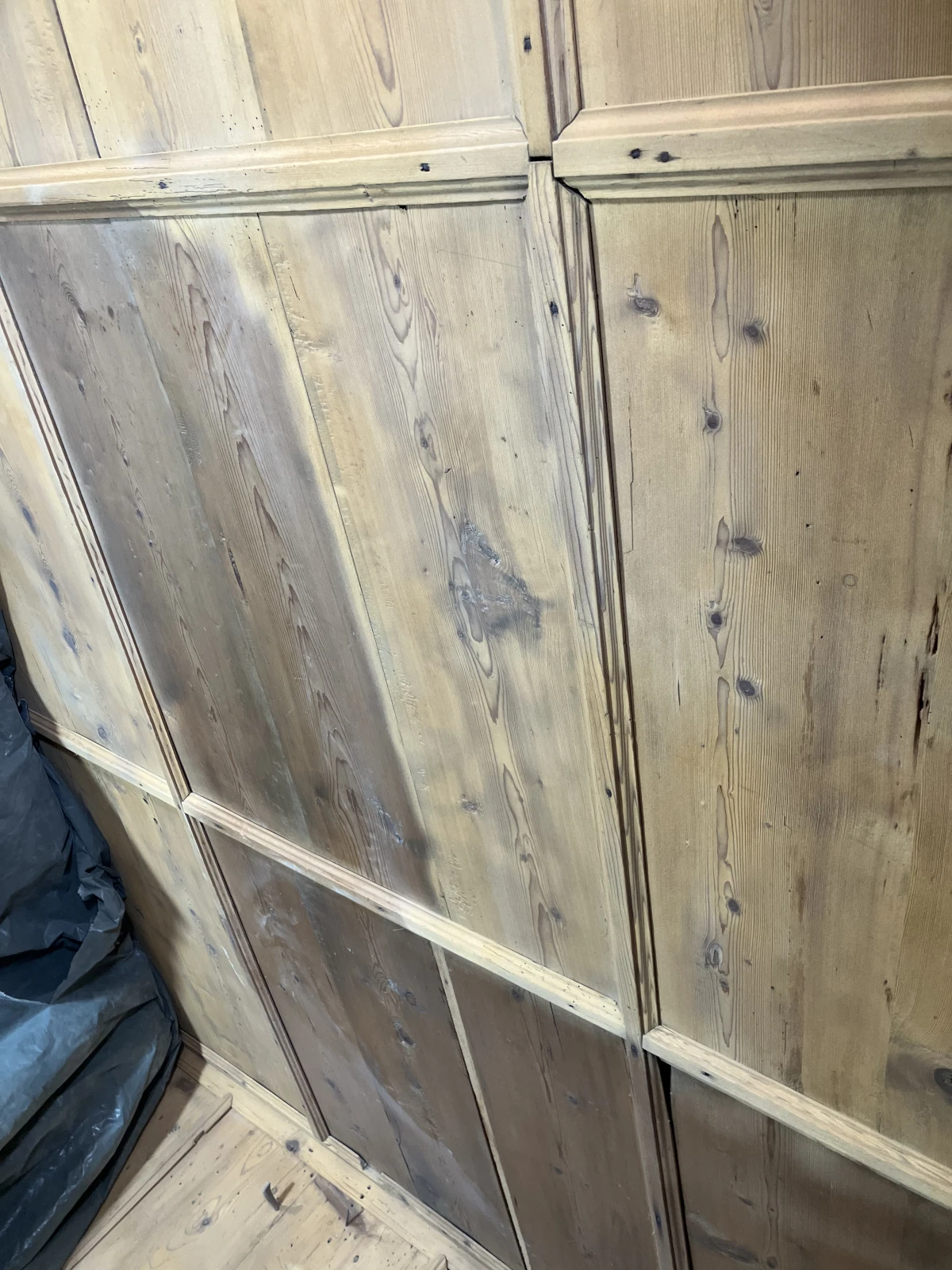 Eine getäfelte Holzwand die mit dem Sandstrahler zur Hälfte gereinigt wurde.