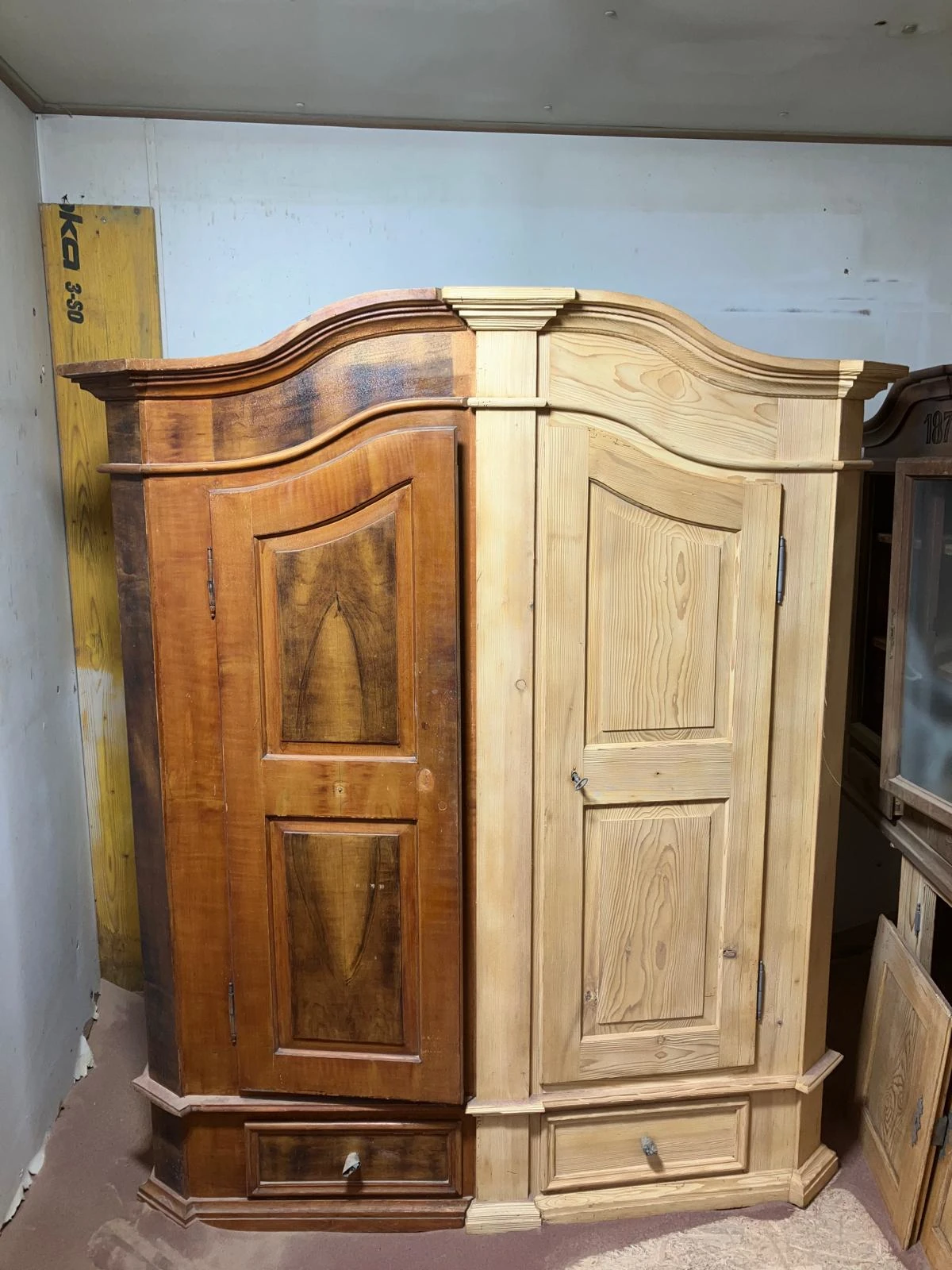 Ein antiker Schrank aus Holz. Eine Hälfte wurde mit dem Sandstrahler gereinigt, die andere ist noch im Originalzustand mit brauner Lasur.